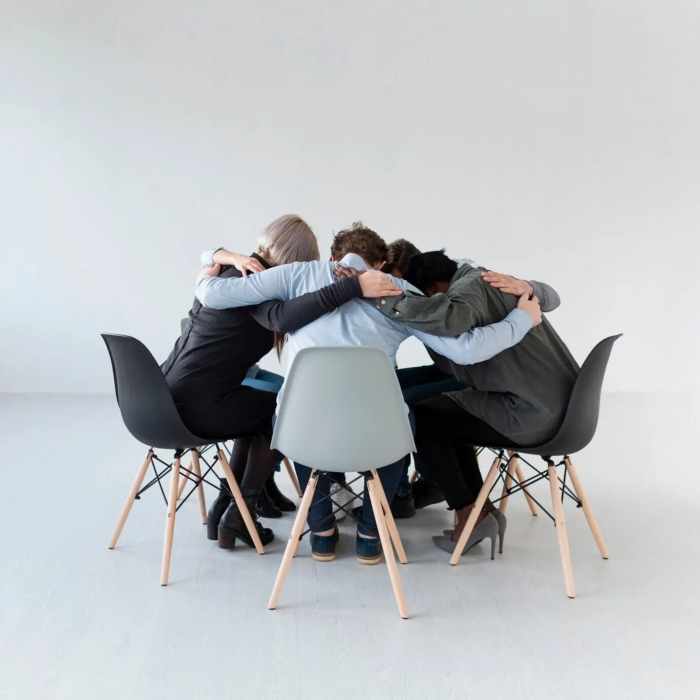 Reha-Patienten stehen auf Stühlen und umarmen sich.